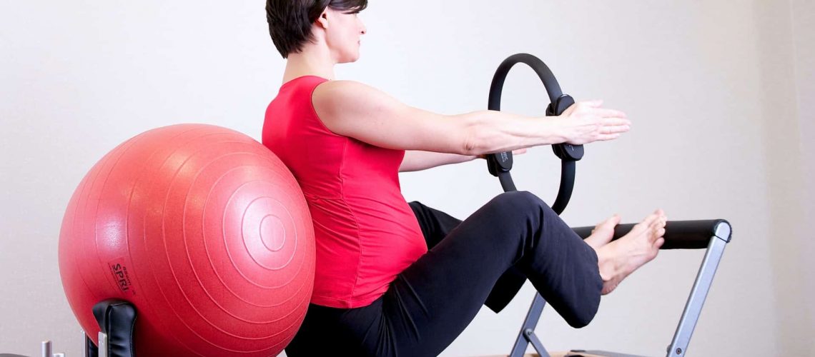 woman-in-red-top-leaning-on-red-stability-ball-1103254